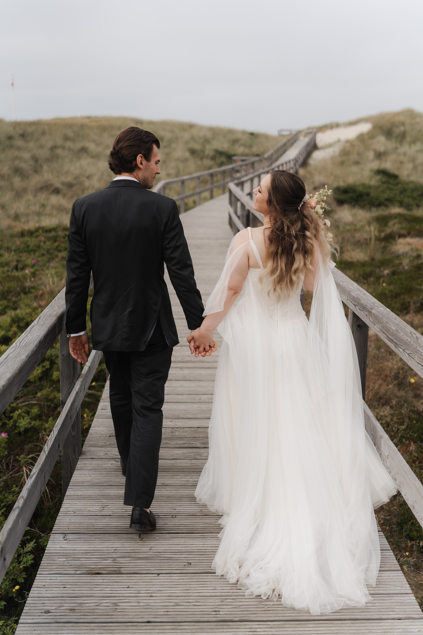 Brautpaar auf dem Holzsteg durch die Dünen auf Sylt, Hochzeitsreportage
