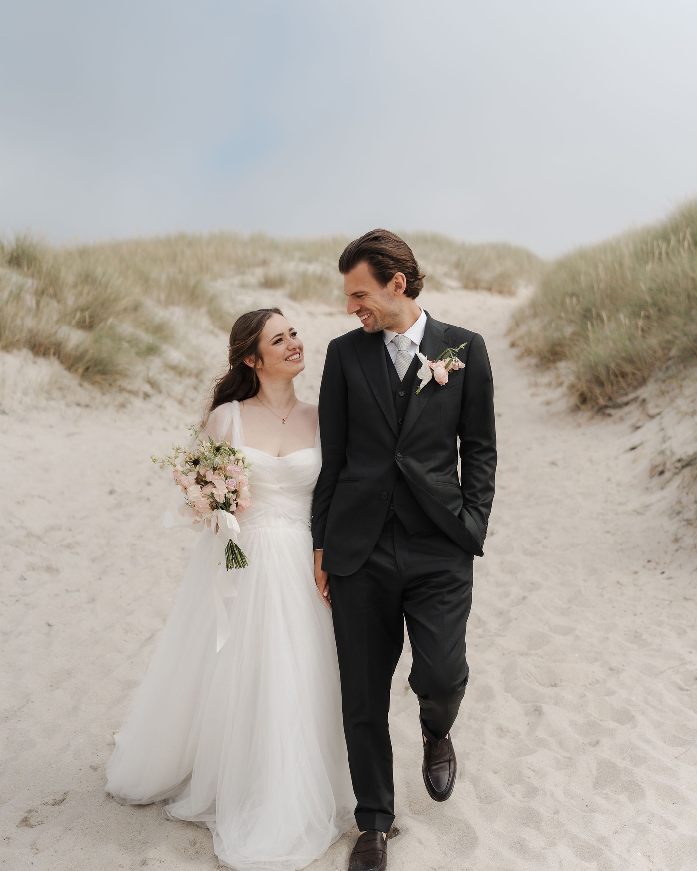 Brautpaar spaziert durch die Dünen auf Sylt, Hochzeitsreportage von Kathi und Chris Photography