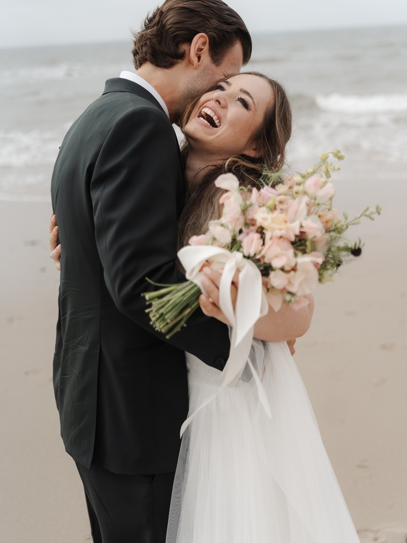 Hochzeitsreportage auf Sylt: Brautpaar lacht am Strand, fotografiert von Kathi und Chris