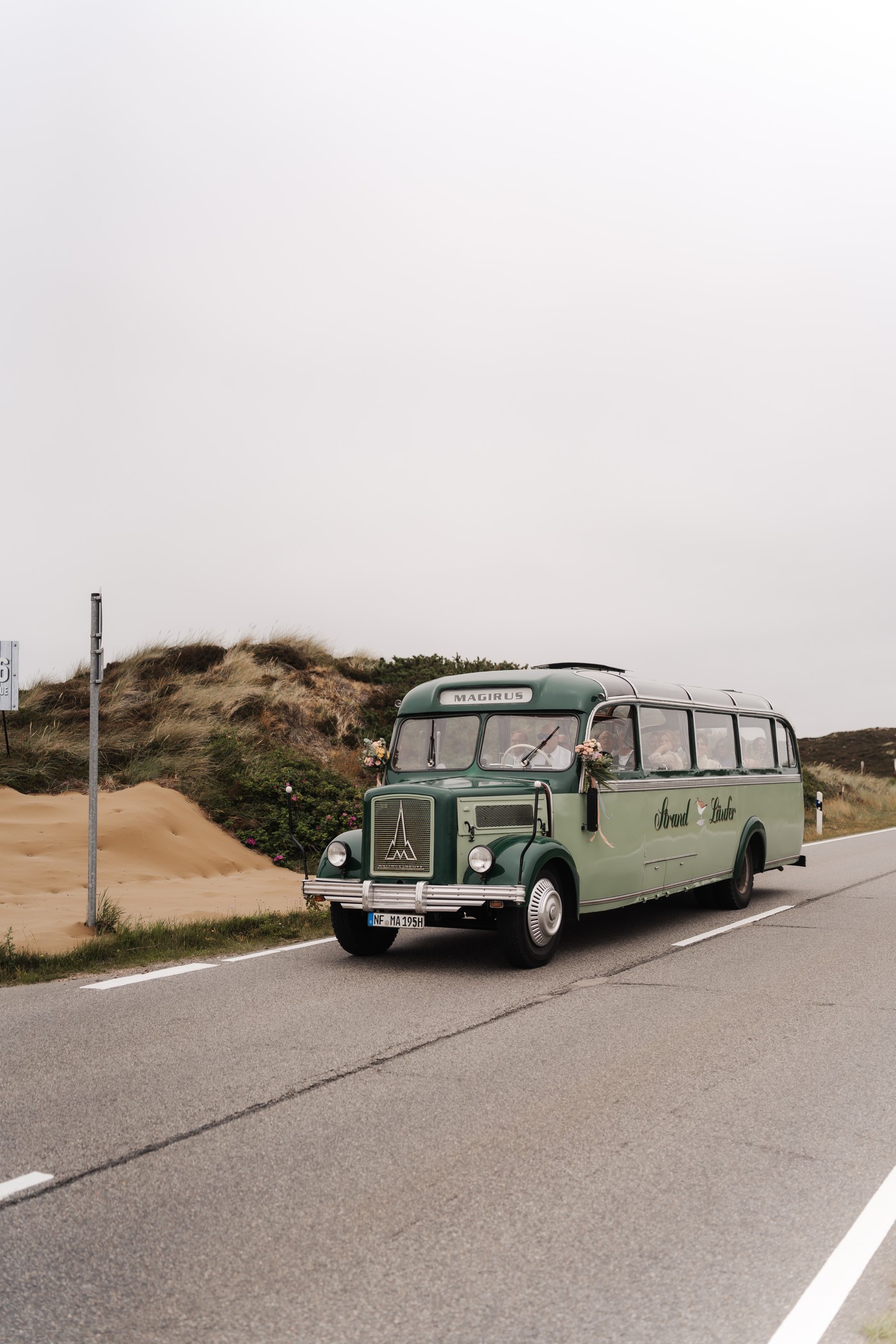 Grüner Magirus-Oldtimerbus auf der Straße durch die Dünen auf Sylt